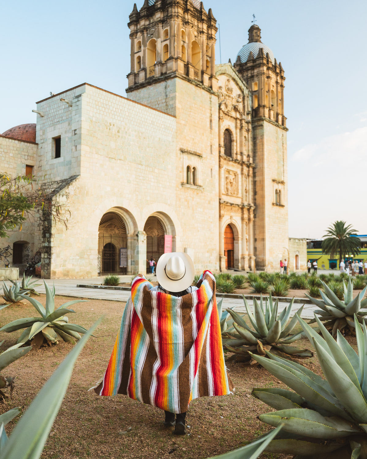 Santo Domingo Church Oaxaca and a girl standing with a handwoven mexican blanket in front of it
