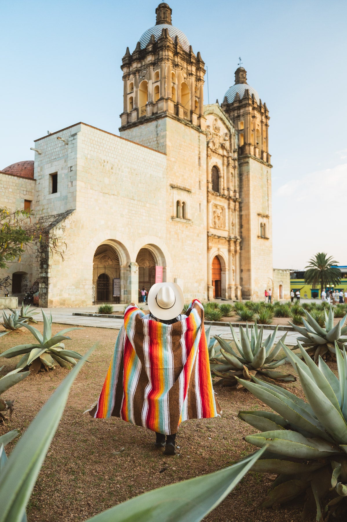 Santo Domingo Church Oaxaca and a girl standing with a handwoven mexican blanket in front of it
