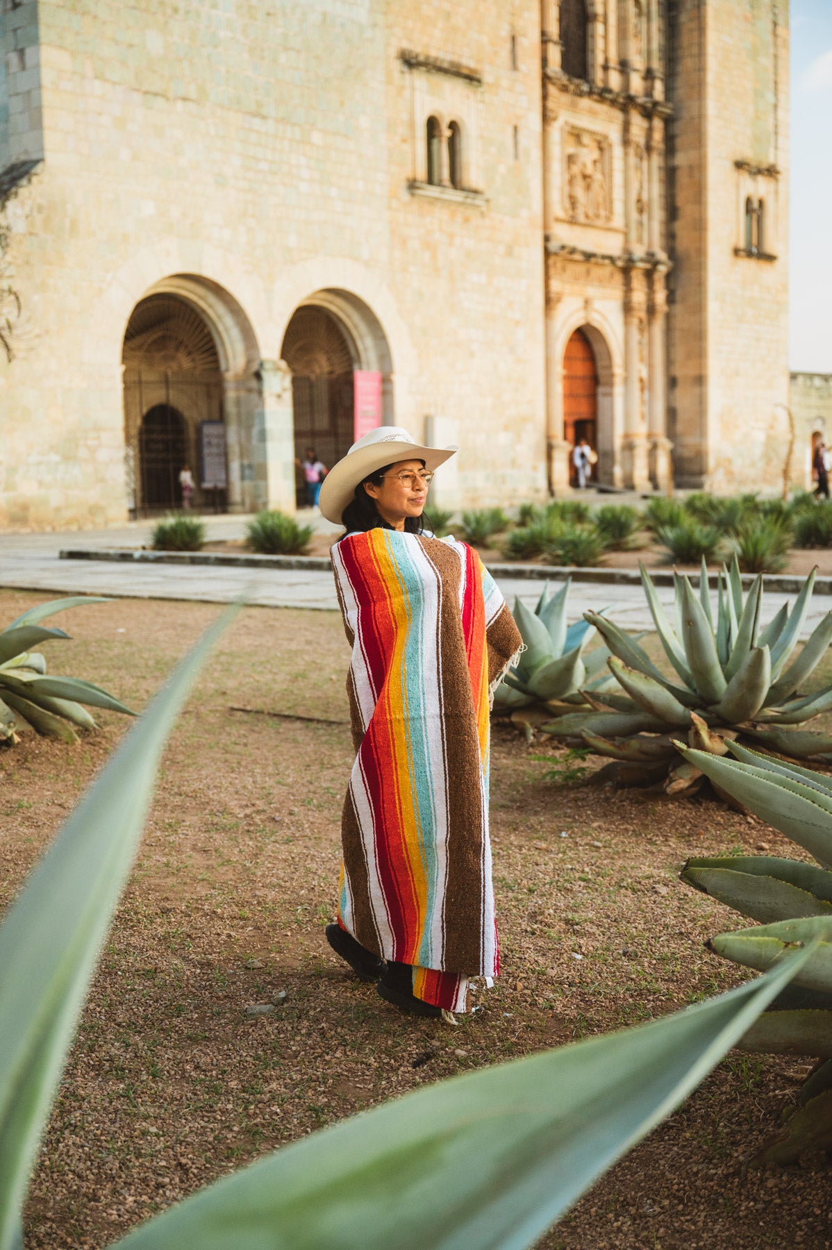Santo Domingo Church Oaxaca and a girl standing with a handwoven mexican blanket in front of it