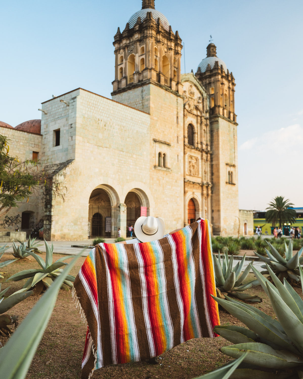 Santo Domingo Church Oaxaca and a girl standing with a handwoven mexican blanket in front of it