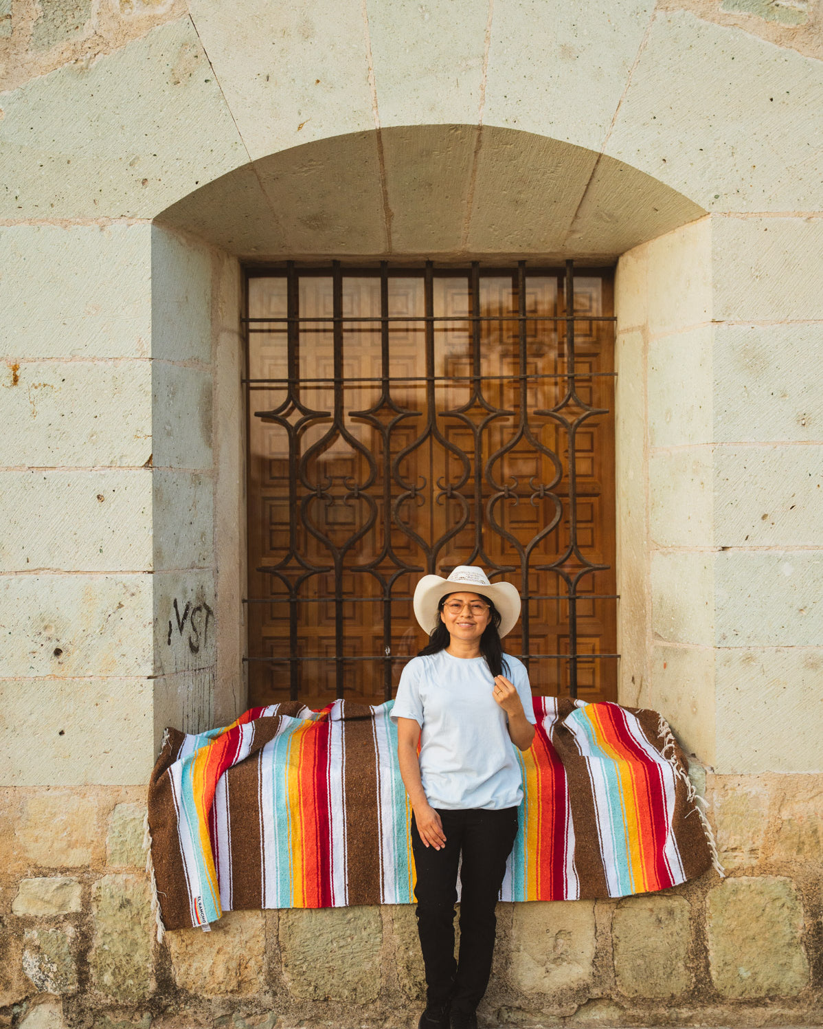 Santo Domingo Church Oaxaca and a girl sitting on a handwoven mexican blanket in front of it