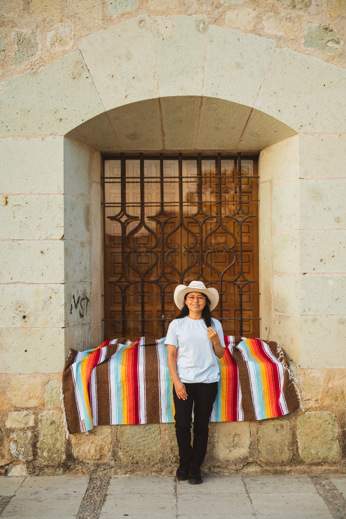 Santo Domingo Church Oaxaca and a girl sitting on a handwoven mexican blanket in front of it