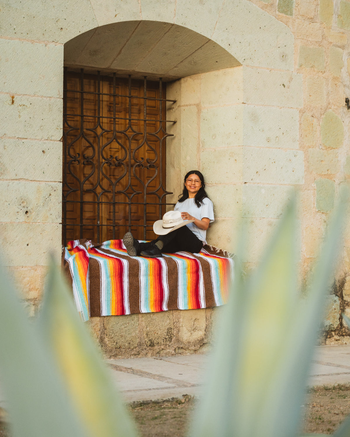 Santo Domingo Church Oaxaca and a girl sitting on a handwoven mexican blanket in front of it