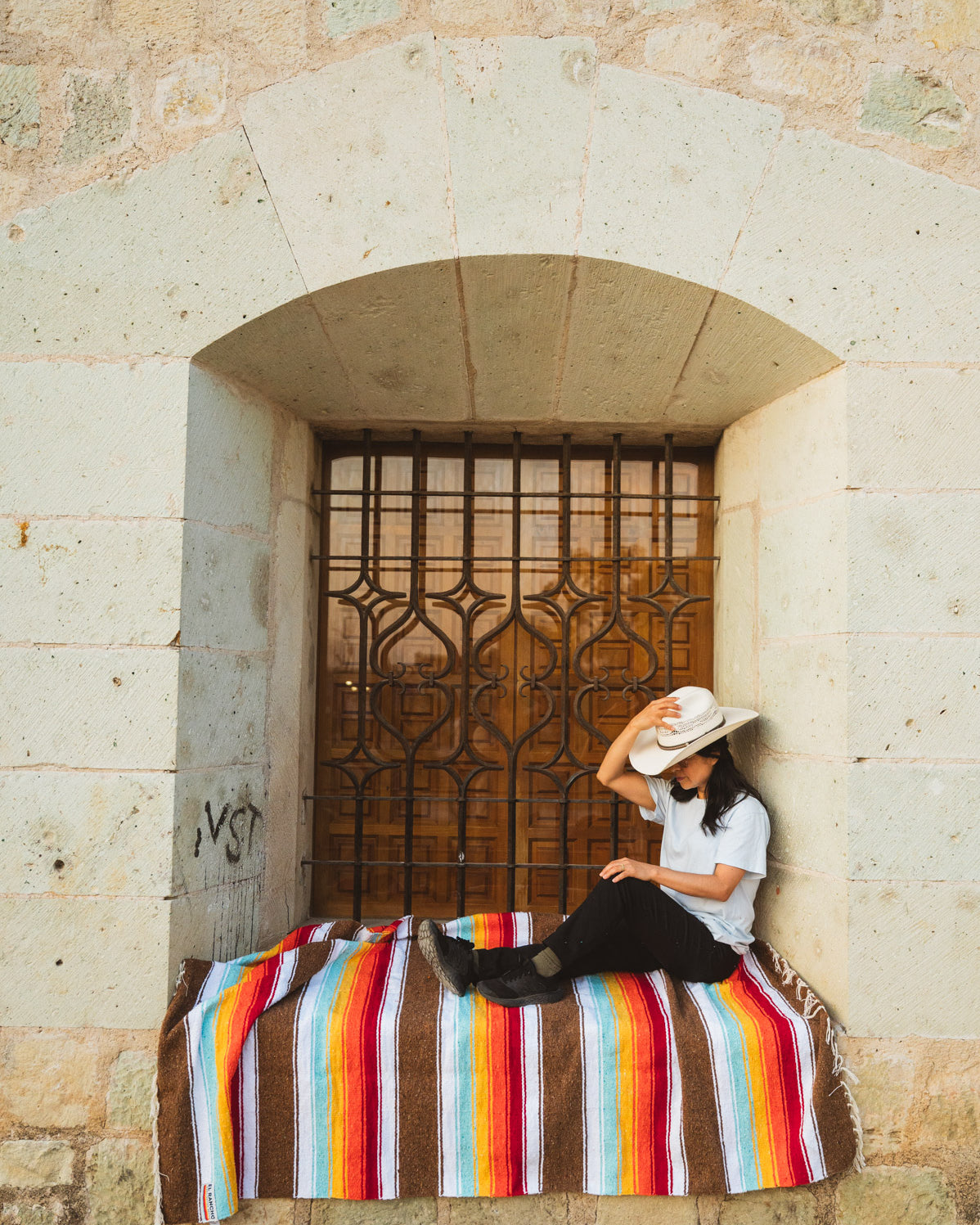Santo Domingo Church Oaxaca and a girl sitting on a handwoven mexican blanket in front of it