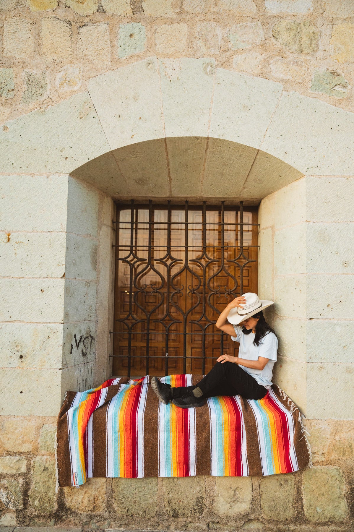 Santo Domingo Church Oaxaca and a girl sitting on a handwoven mexican blanket in front of it