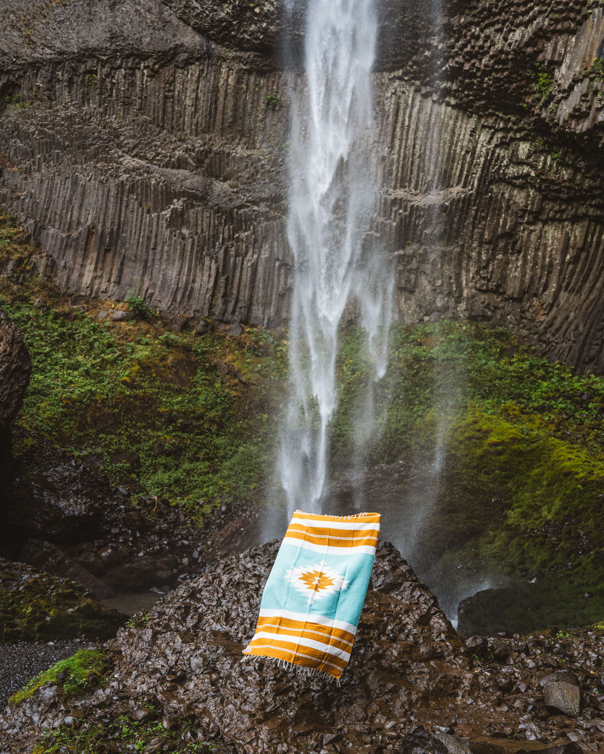 turquoise and gold mexican blanket in front of a waterfall