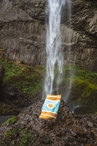 turquoise and gold mexican blanket in front of a waterfall