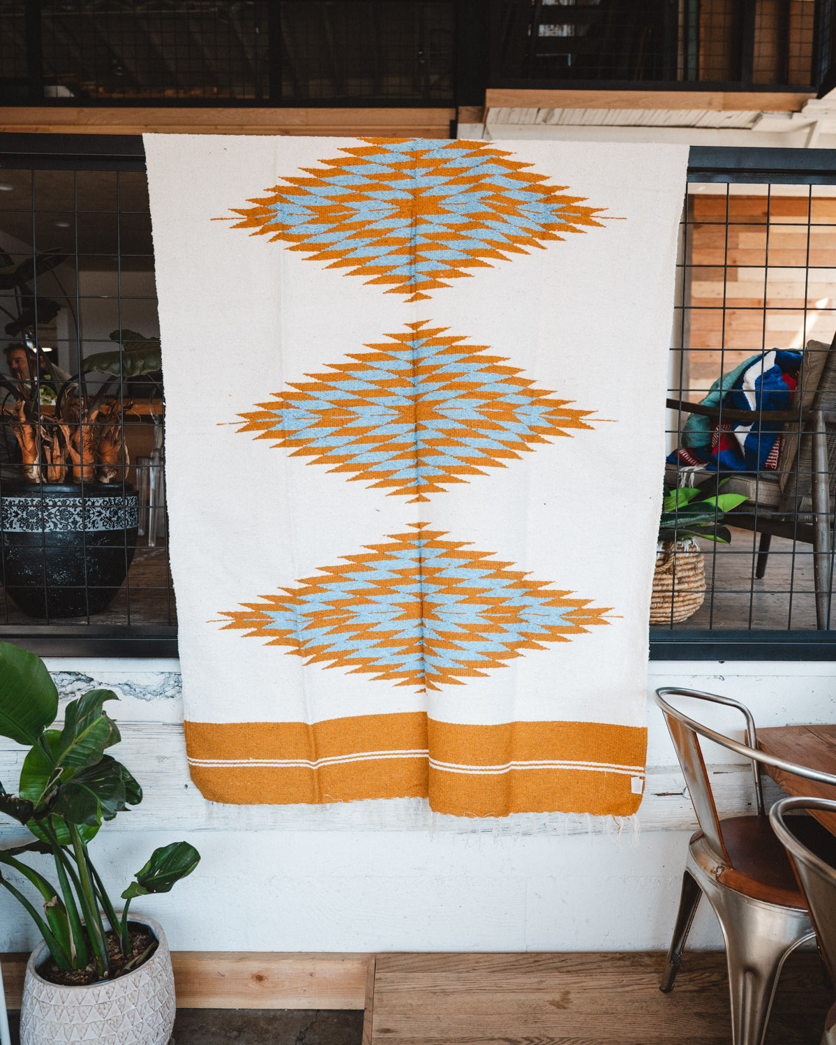 Handwoven Mexican Blanket Turquoise and gold color 3 Diamond pattern in modern industrial setting