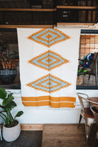 Handwoven Mexican Blanket Turquoise and gold color 3 Diamond pattern in modern industrial setting