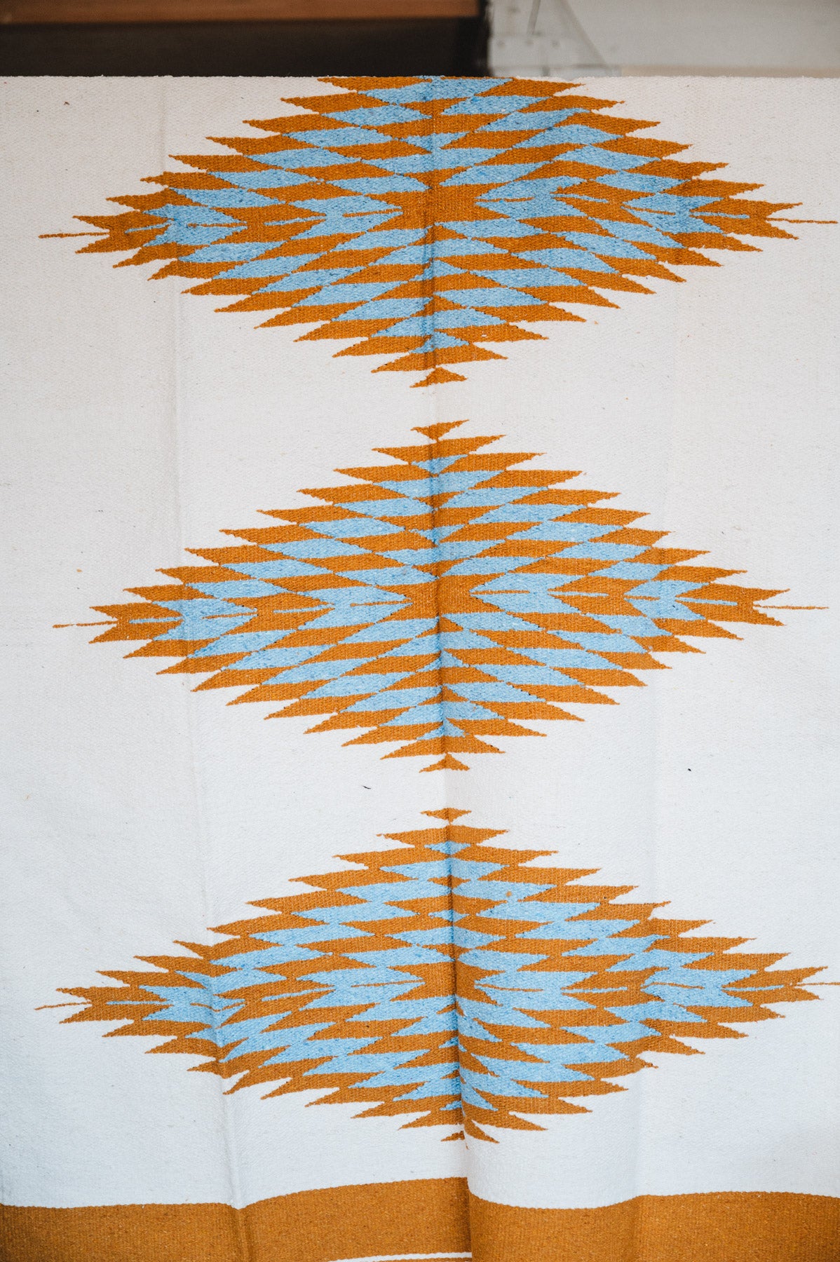 Handwoven Mexican Blanket Turquoise and gold color 3 Diamond pattern in modern industrial setting