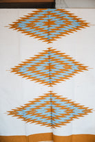 Handwoven Mexican Blanket Turquoise and gold color 3 Diamond pattern in modern industrial setting