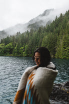 Woman in the olympic peninsula PNW wrapped in a turquoise and gold handwoven mexican diamond blanket