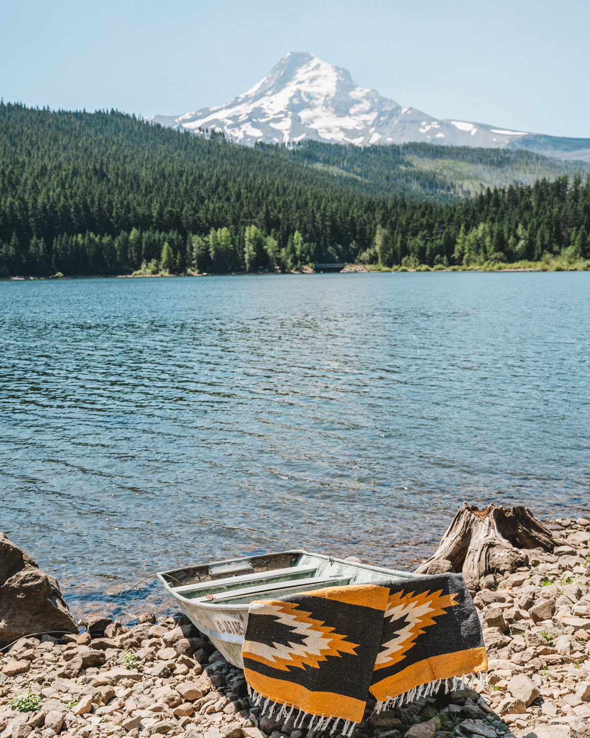 yellow and black zapotec relampago blanket laying on a boat in front of mountain lake