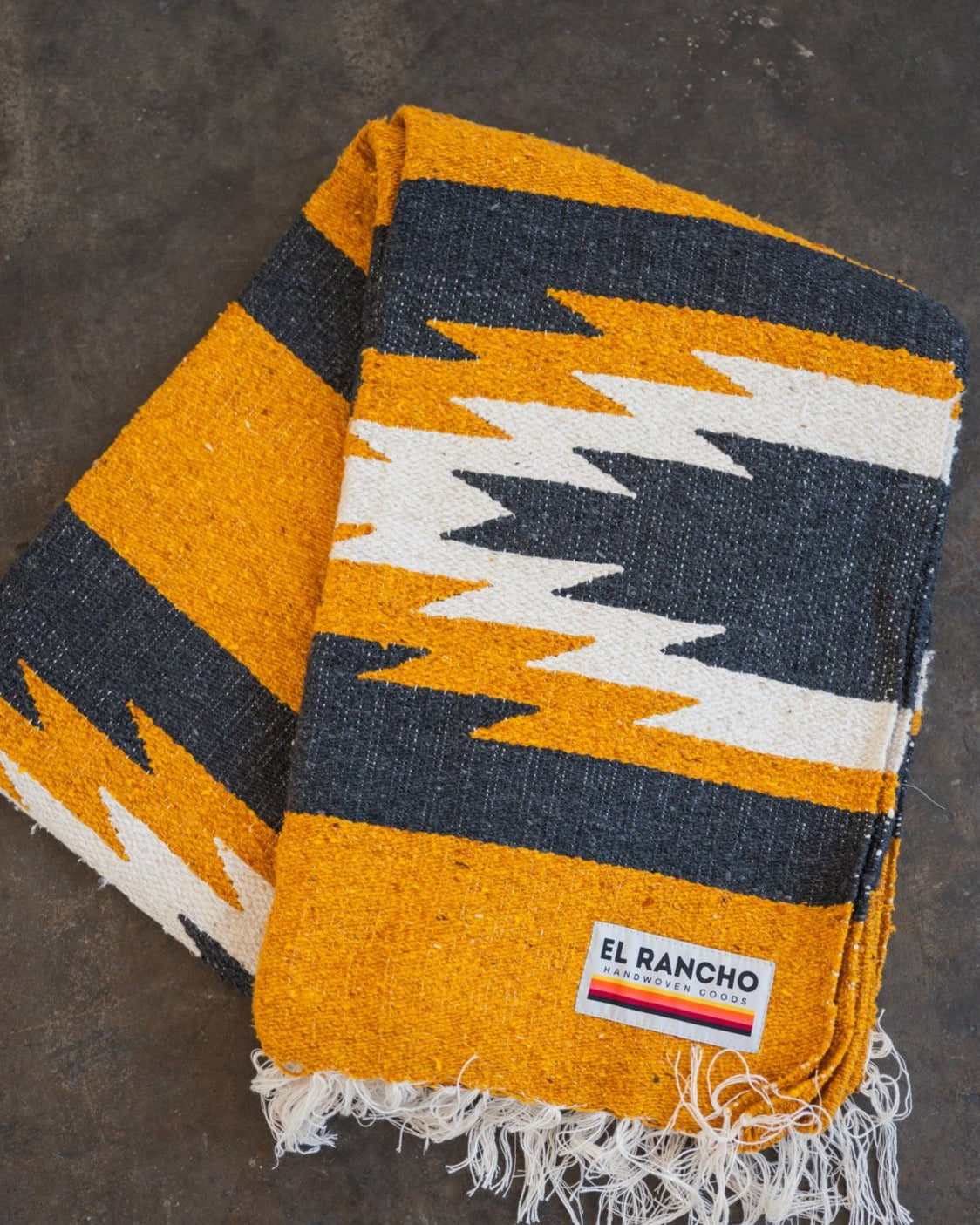 yellow and black relampago blanket laying folded on concrete floor