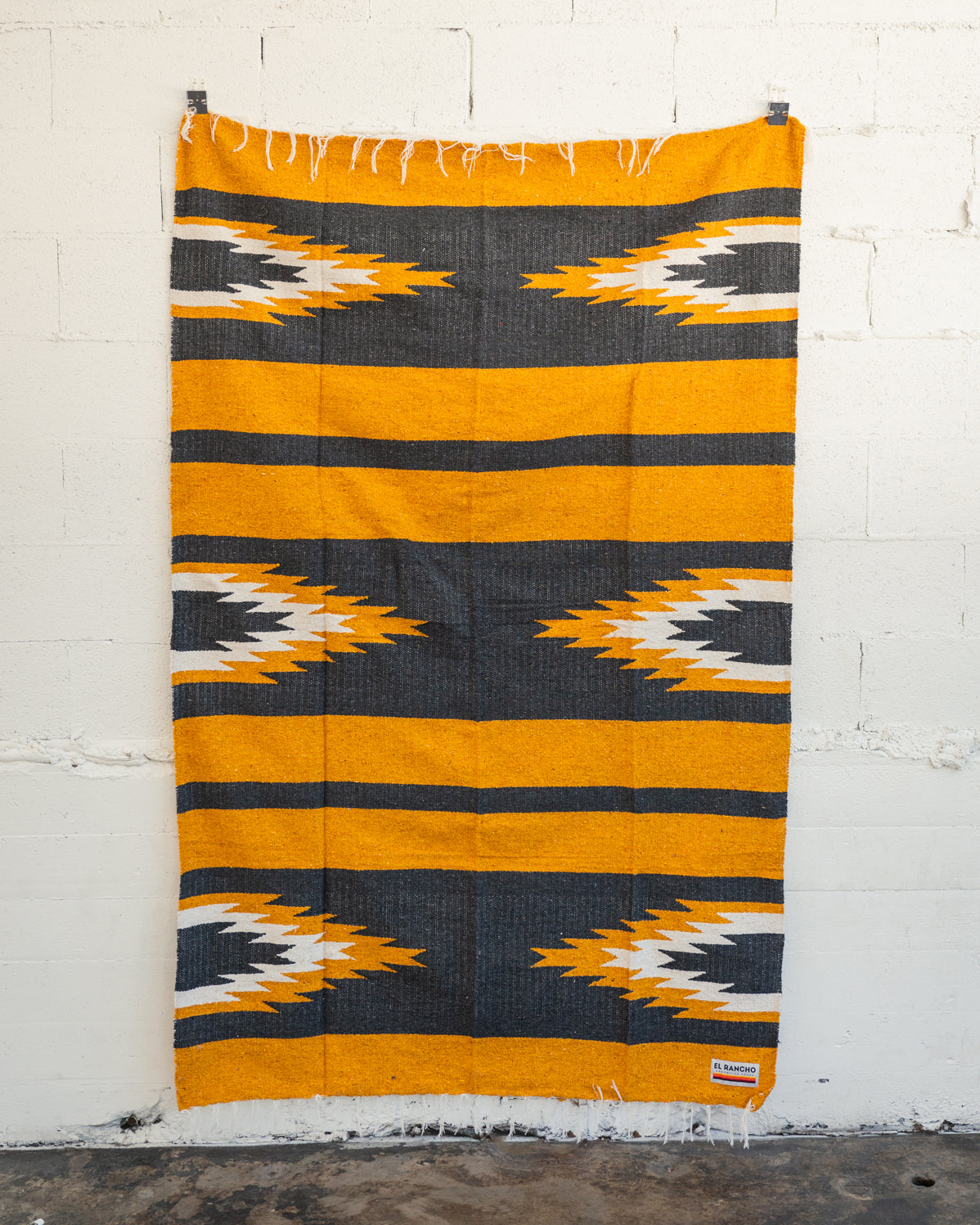 yellow and black relampago blanket hanging from white brick wall
