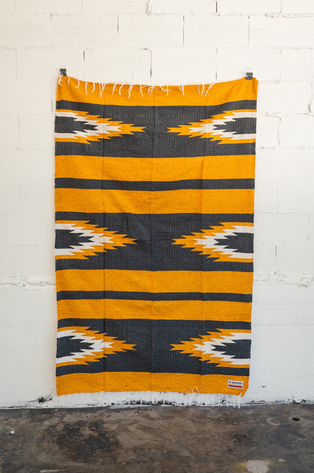 yellow and black relampago blanket hanging from white brick wall