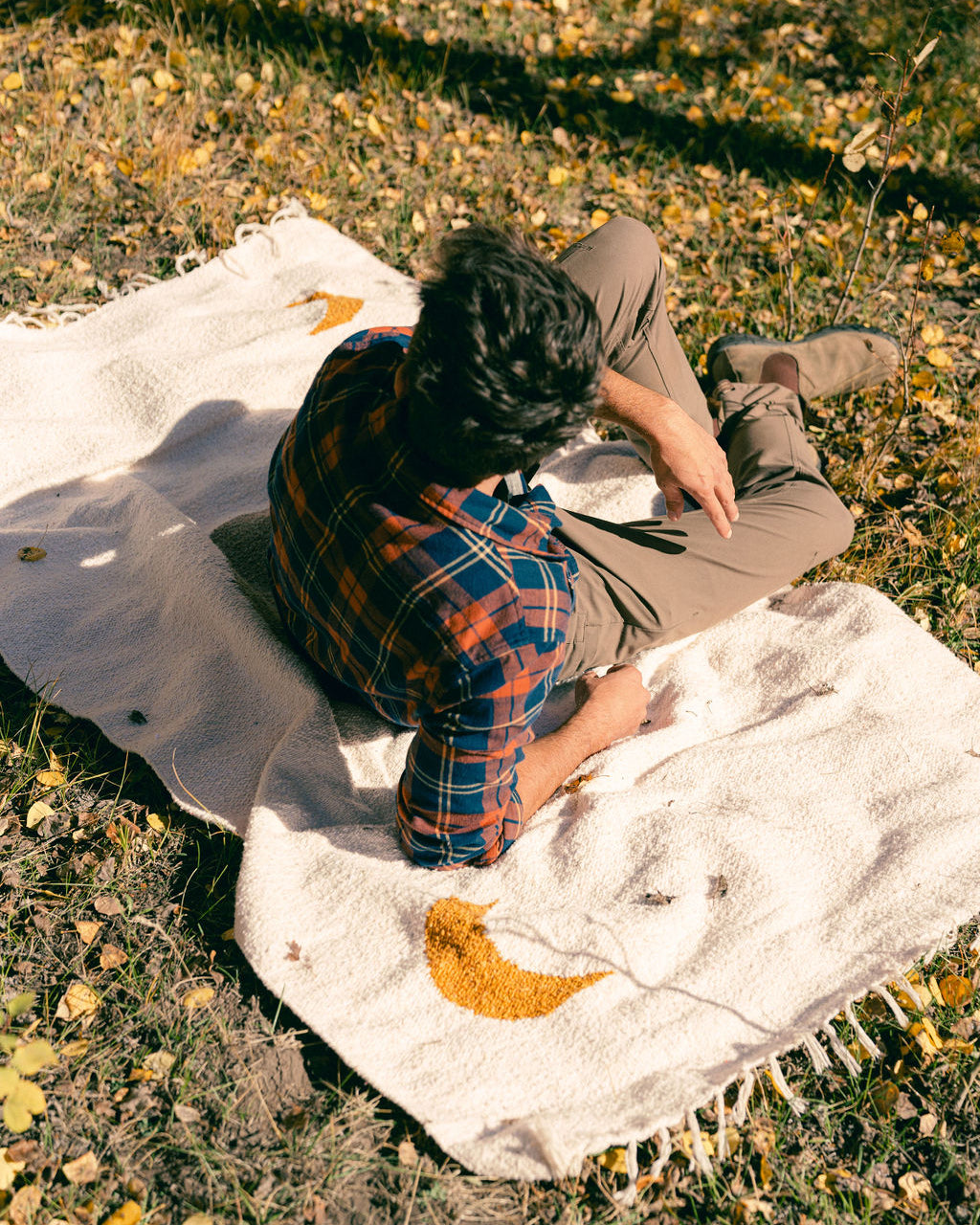man sitting on cream blanket in the grass