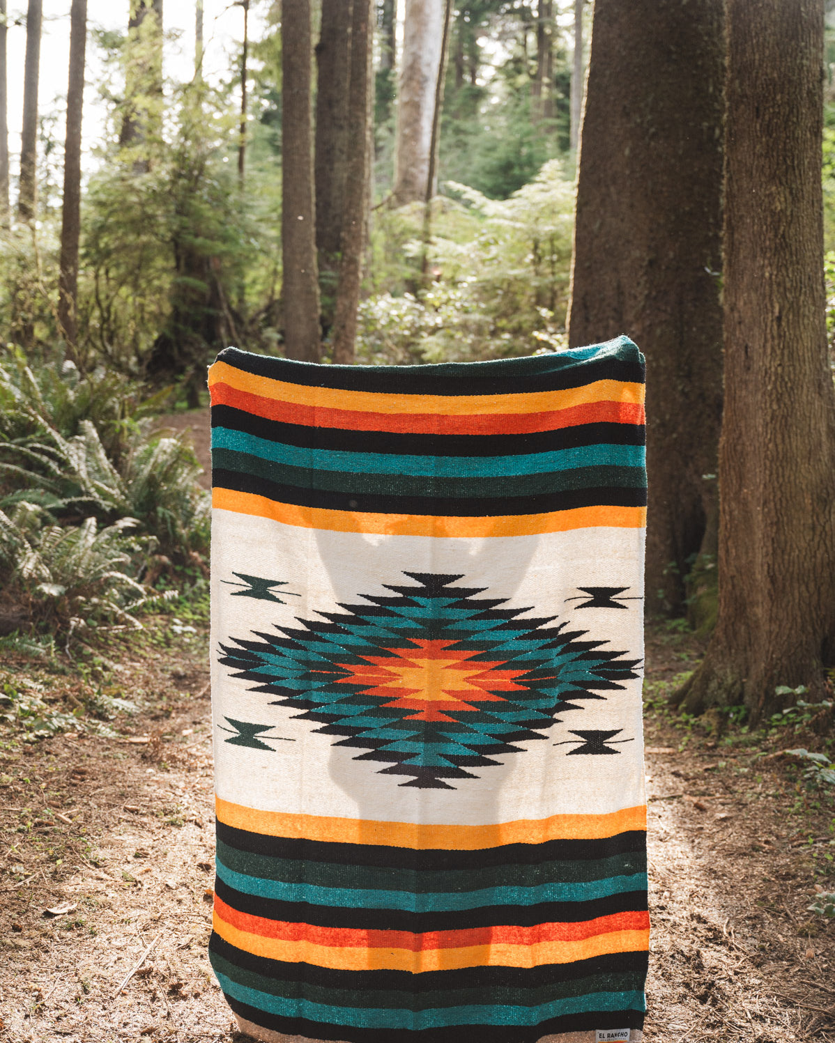 handwoven mexican diamond blanket being held in the forest