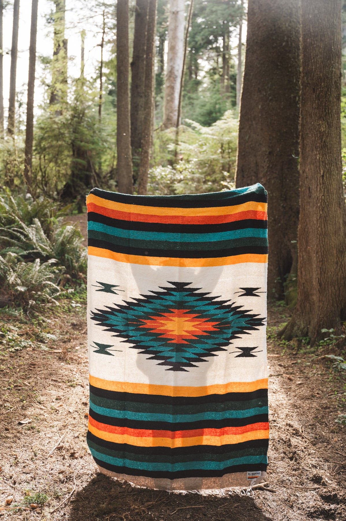 handwoven mexican diamond blanket being held in the forest
