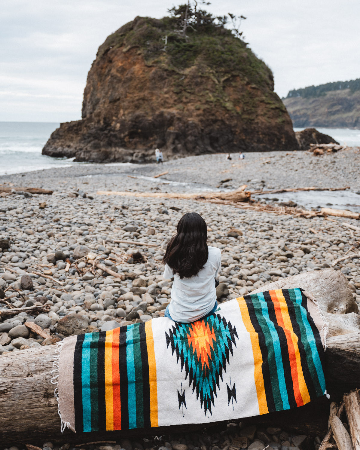 girl sitting on handwoven mexican blanket on the beach in the Pacific northwest