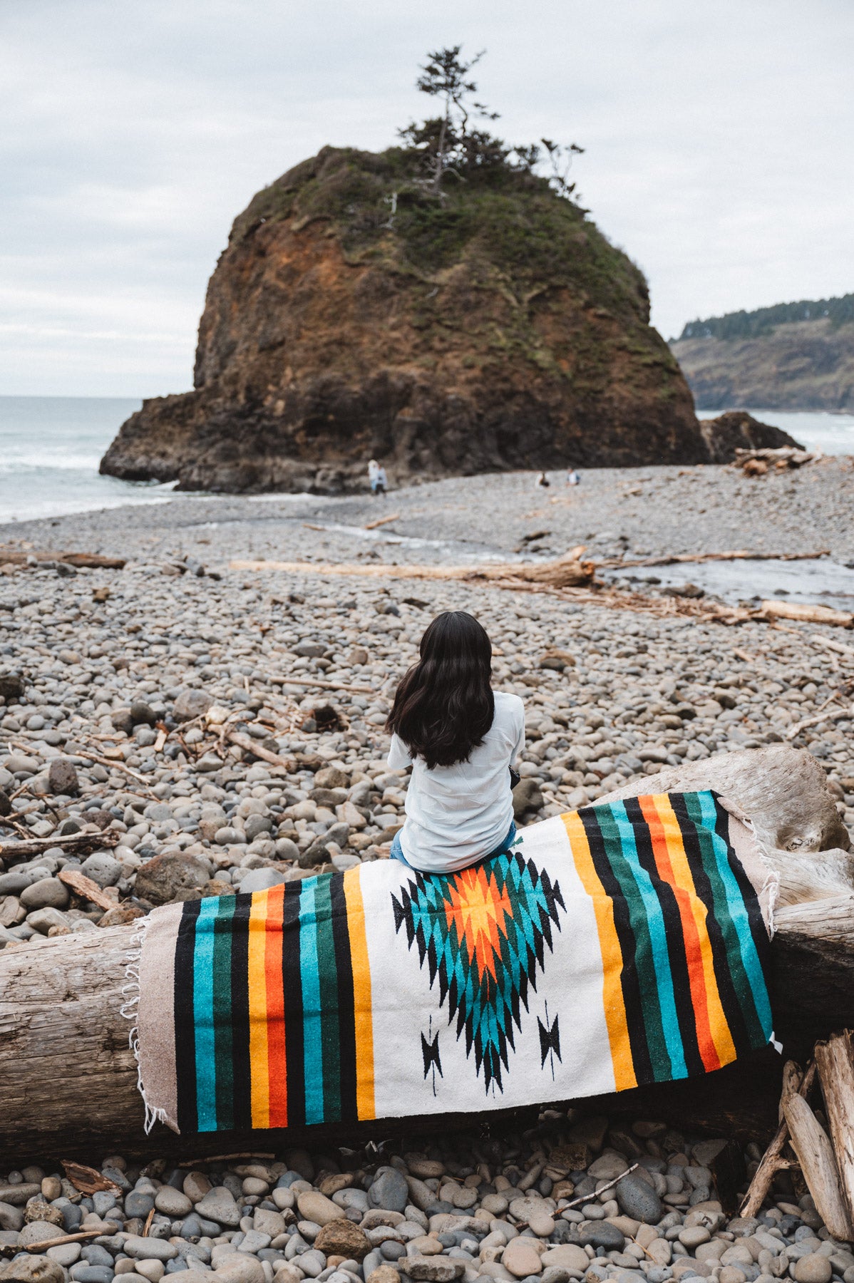 girl sitting on handwoven mexican blanket on the beach in the Pacific northwest