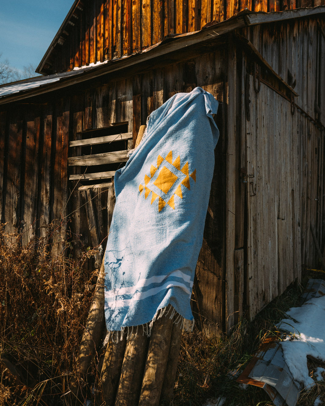 blue mexican blanket hanging from a barn