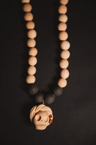 Necklace with wooden beads and a skull pendant on a dark background
