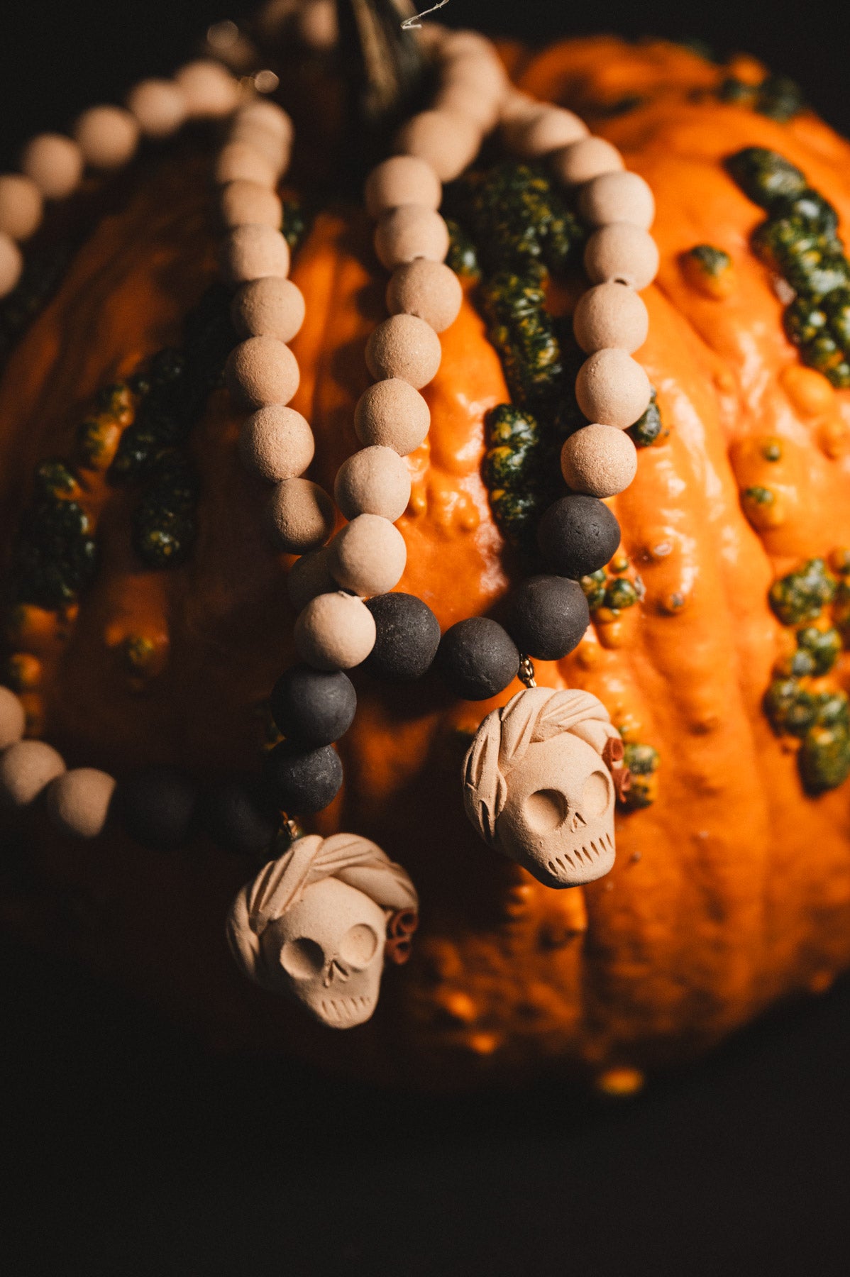 Decorative beaded necklace with skull pendants on a pumpkin background