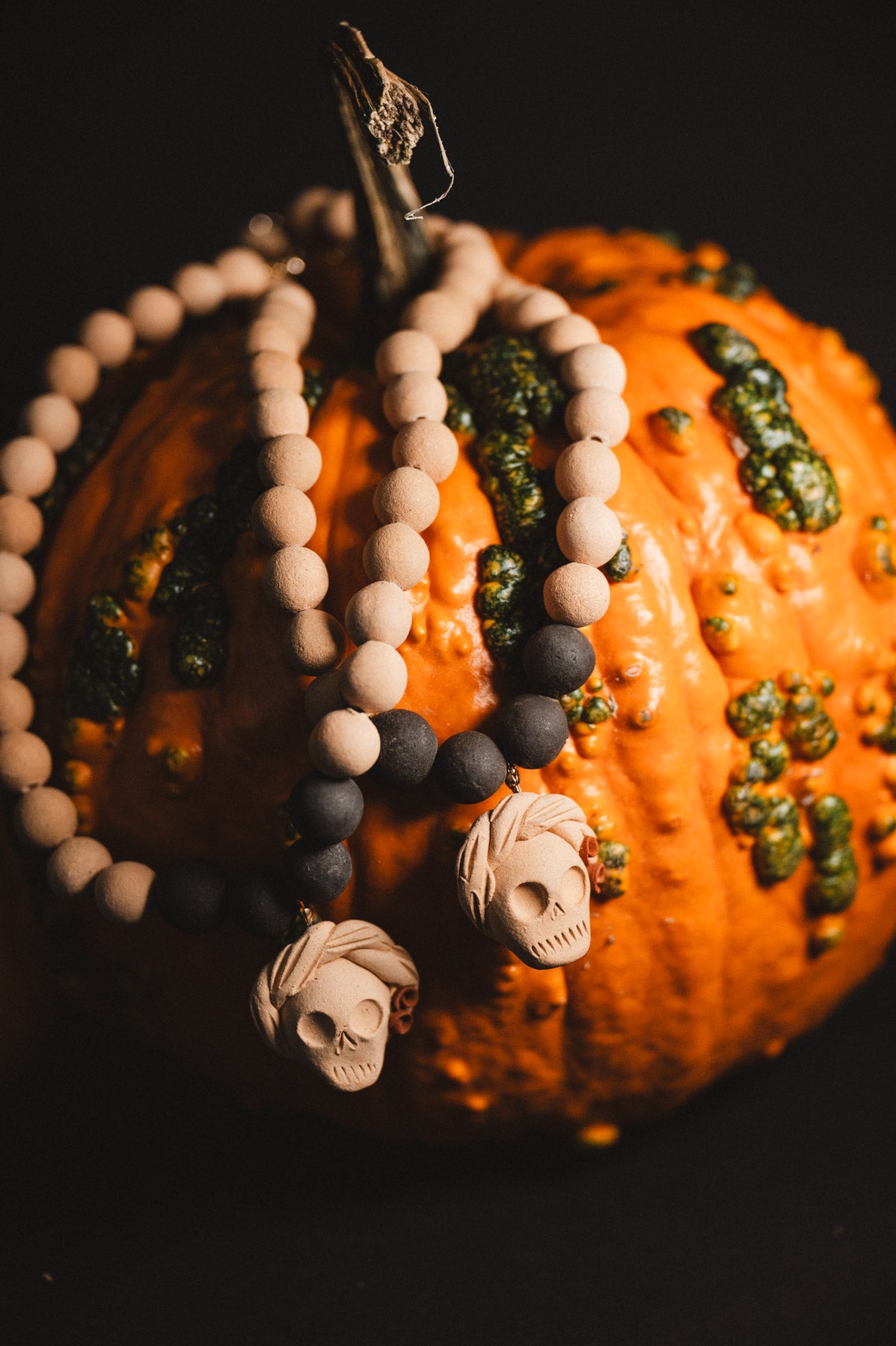 Decorative pumpkin with beaded necklace and skull pendant on a dark background