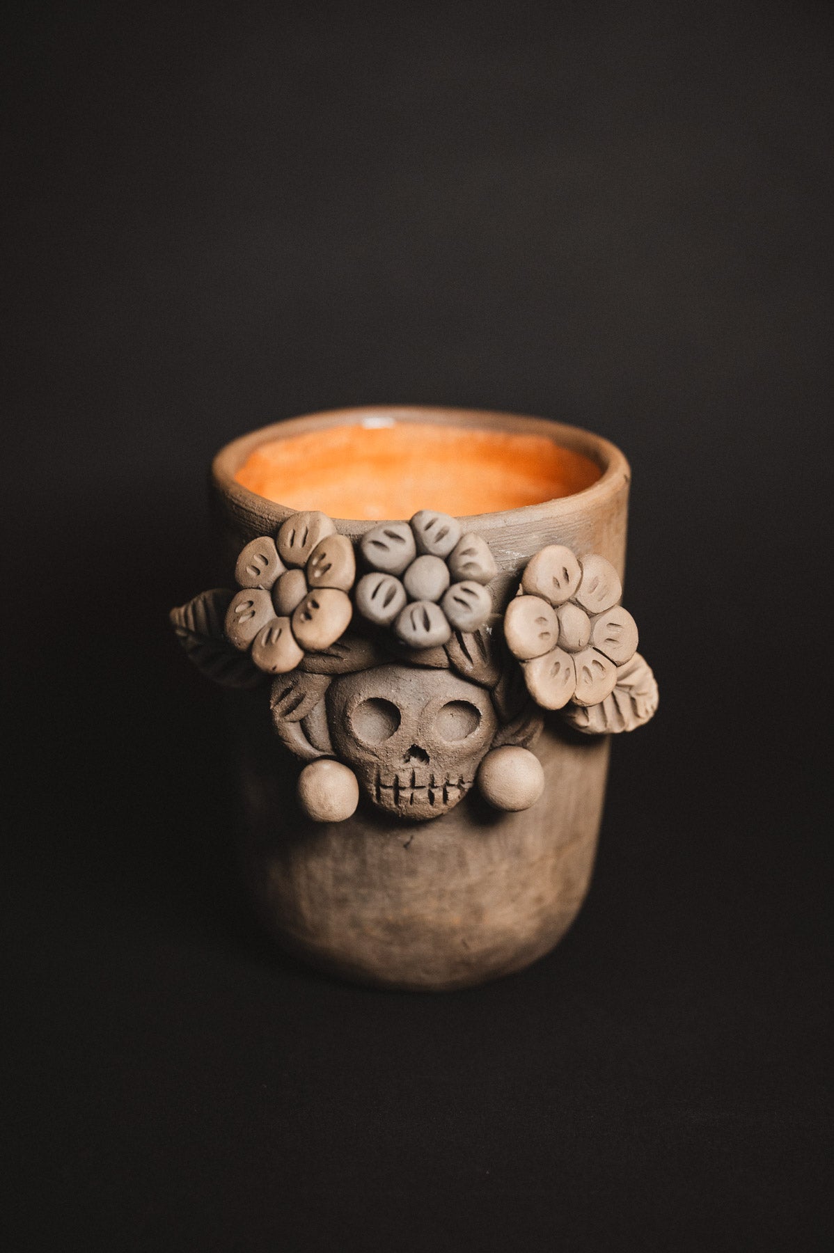 Ceramic cup with skull and floral design on a black background