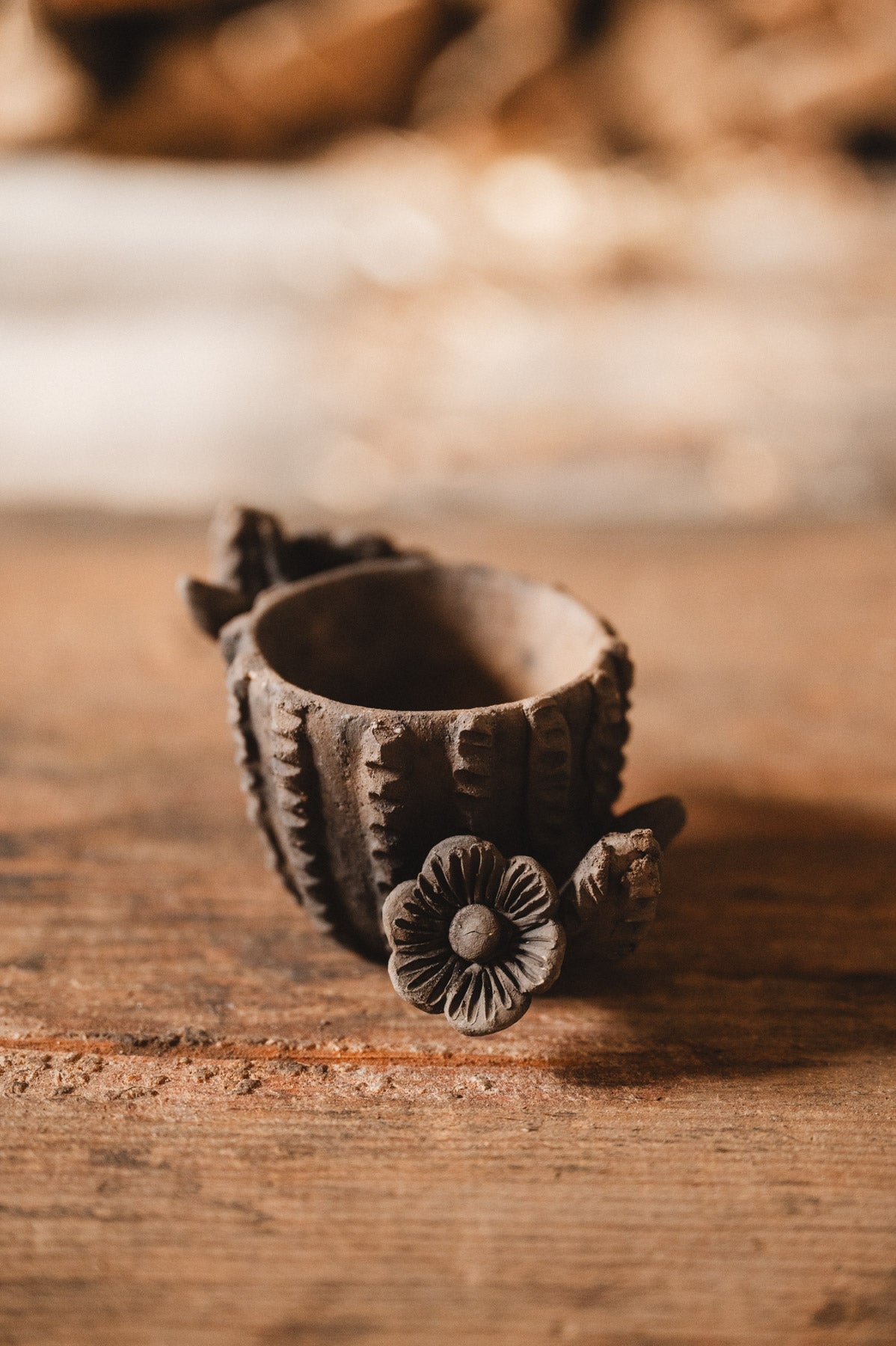 Decorative clay cactus planter with floral design on a wooden surface