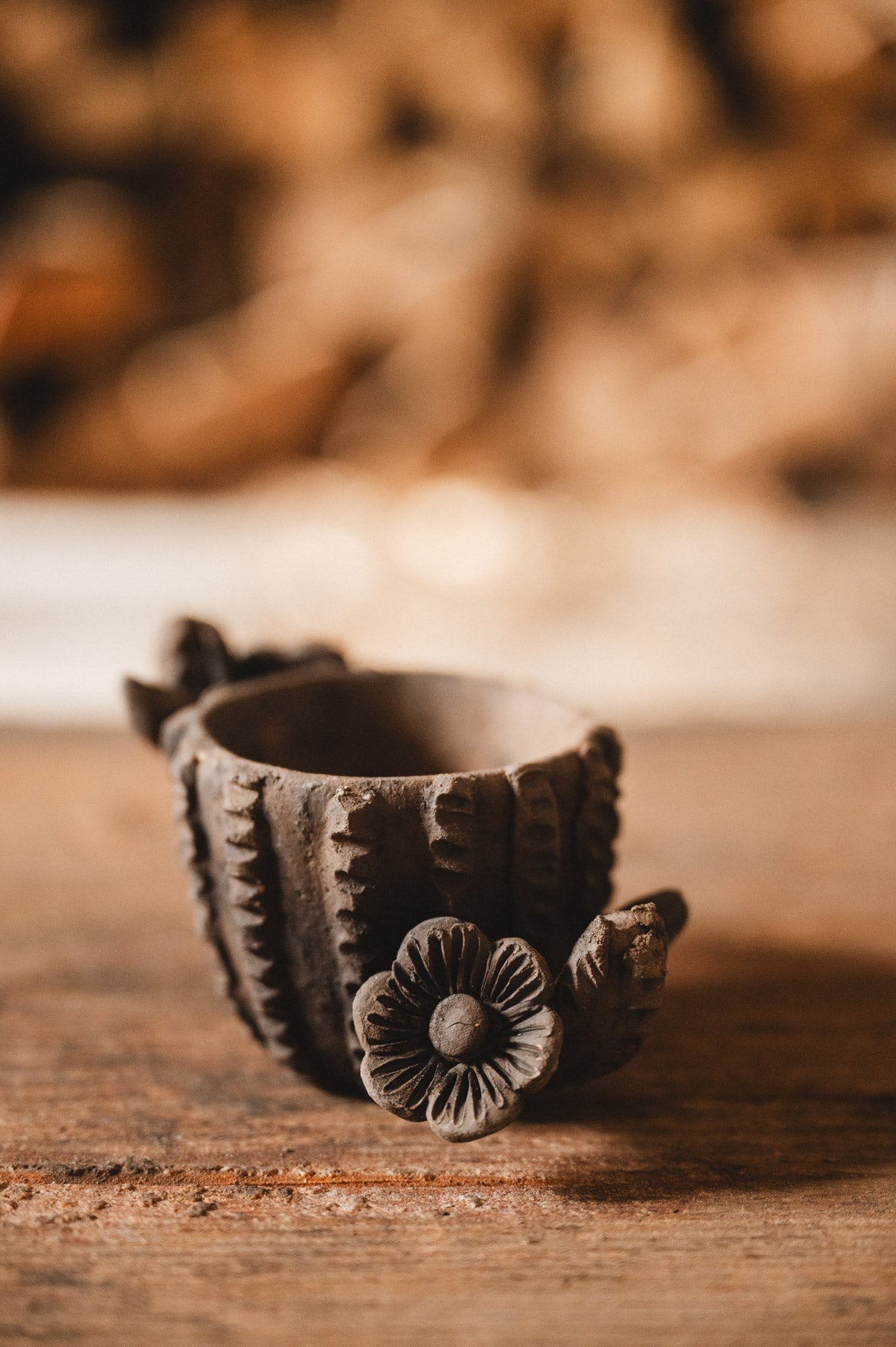 Decorative clay cactus planter with floral design on a wooden surface