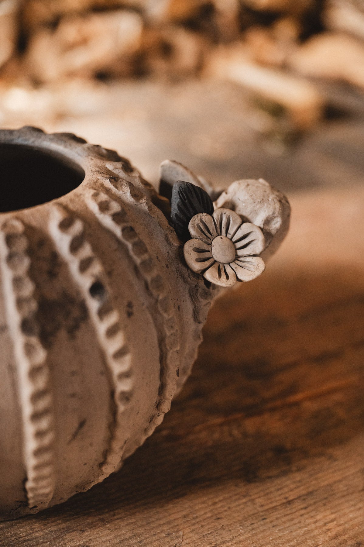 Ceramic cactus planter with floral design on a wooden surface with blurred woodpile background