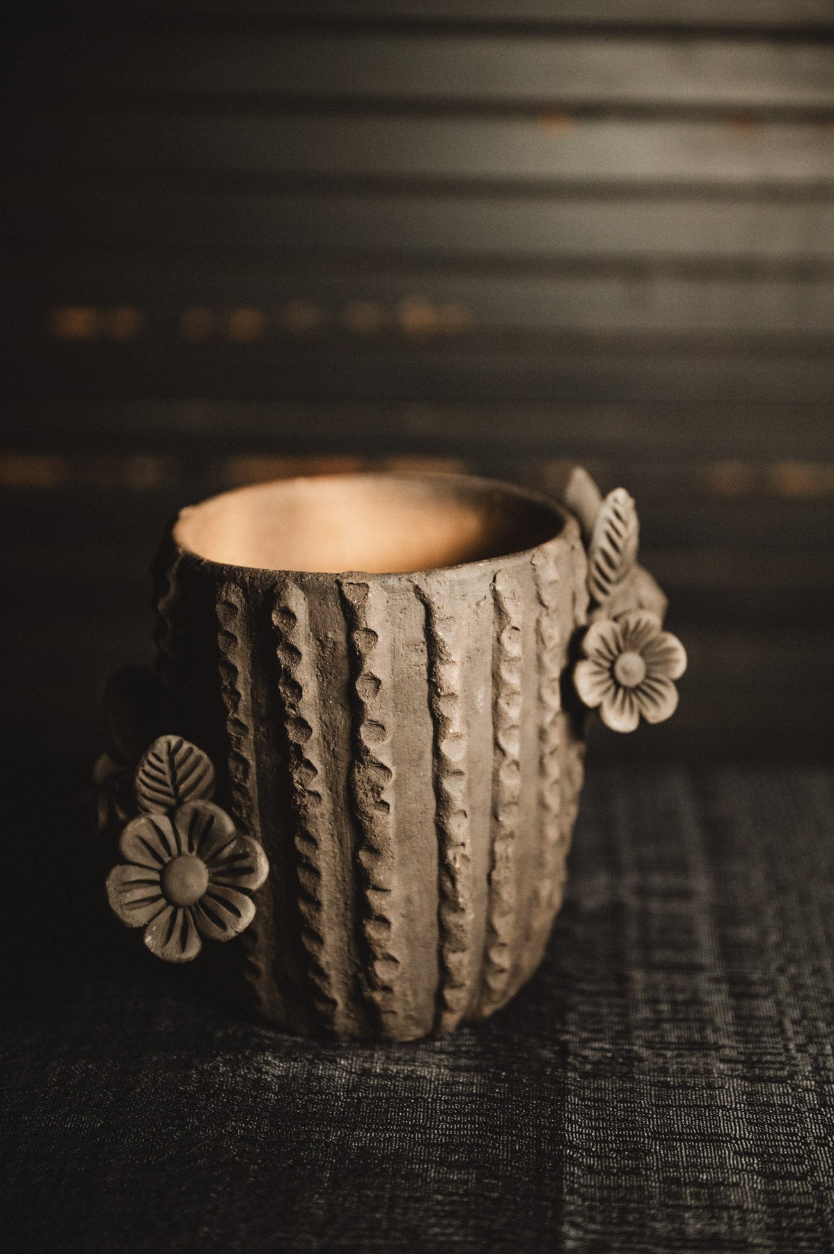 Ceramic planter with floral designs on a dark textured background