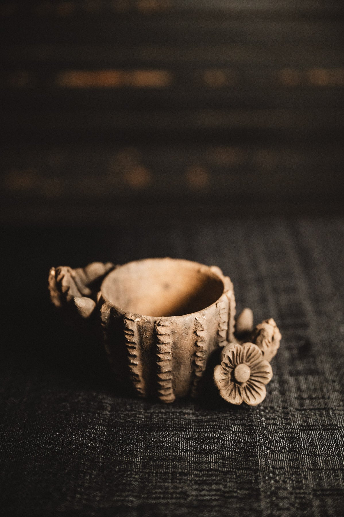 Decorative ceramic planter with floral design on a dark textured surface