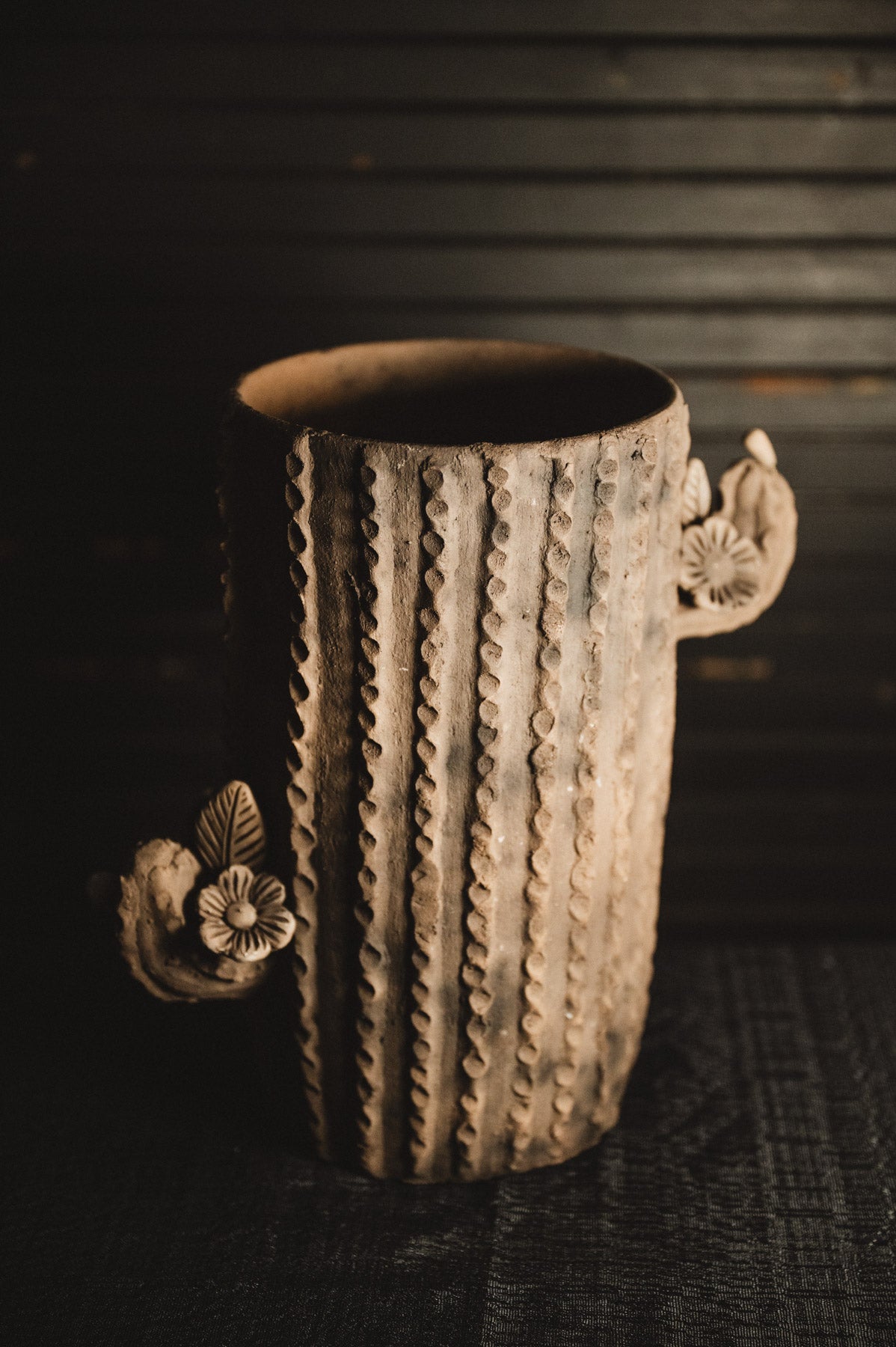Decorative ceramic planter with floral designs on a dark background