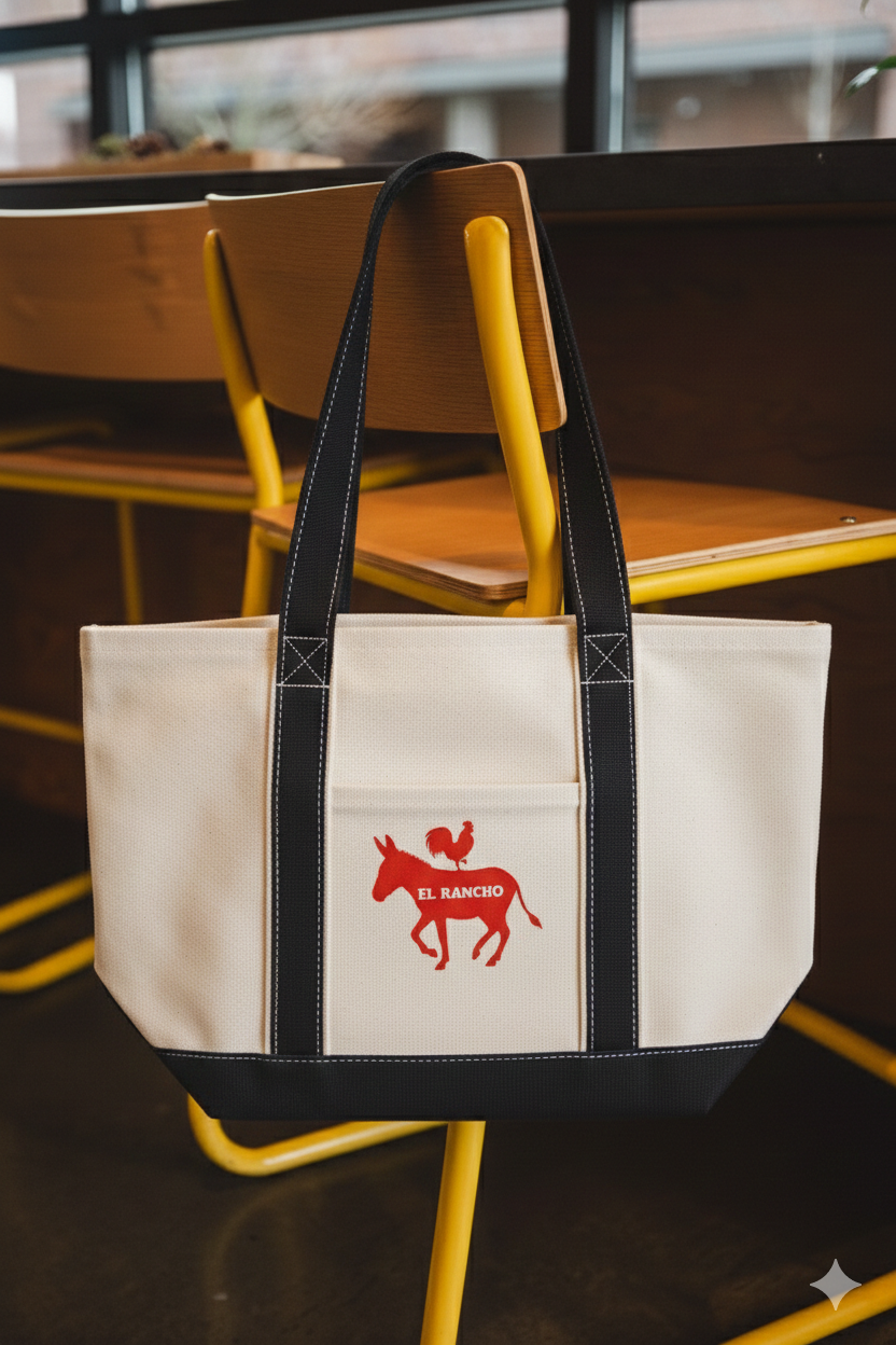 Beige tote bag with red logo on a chair in a blurred indoor setting