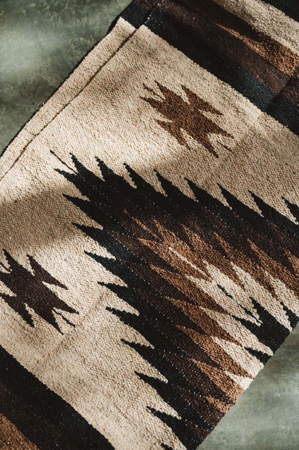 Handwoven brown and beige diamond mexican blanket folded on ground