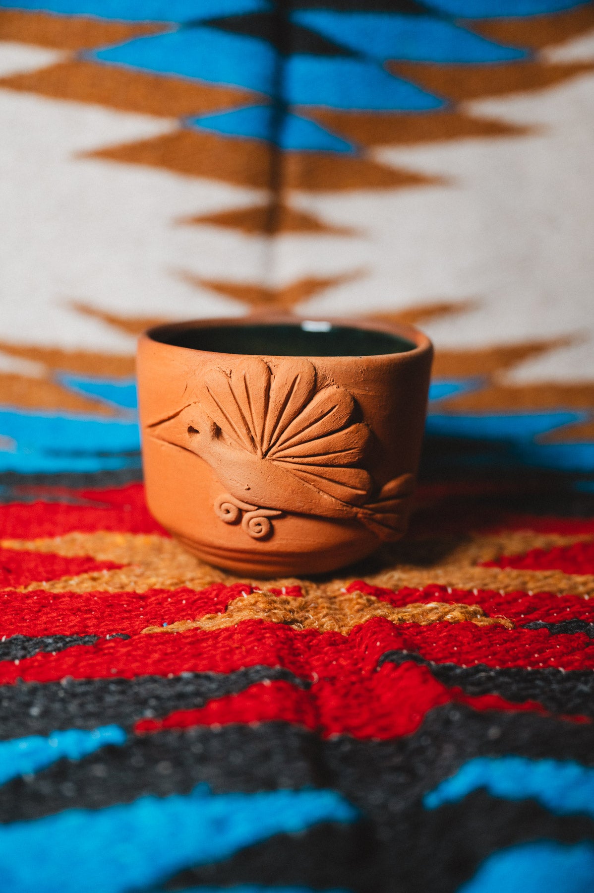 Ceramic cup with shell design on a colorful patterned fabric background