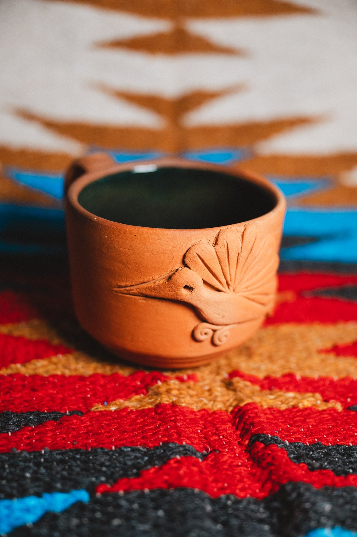 Ceramic mug with bird design on a colorful patterned surface