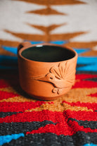Ceramic mug with bird design on a colorful patterned surface