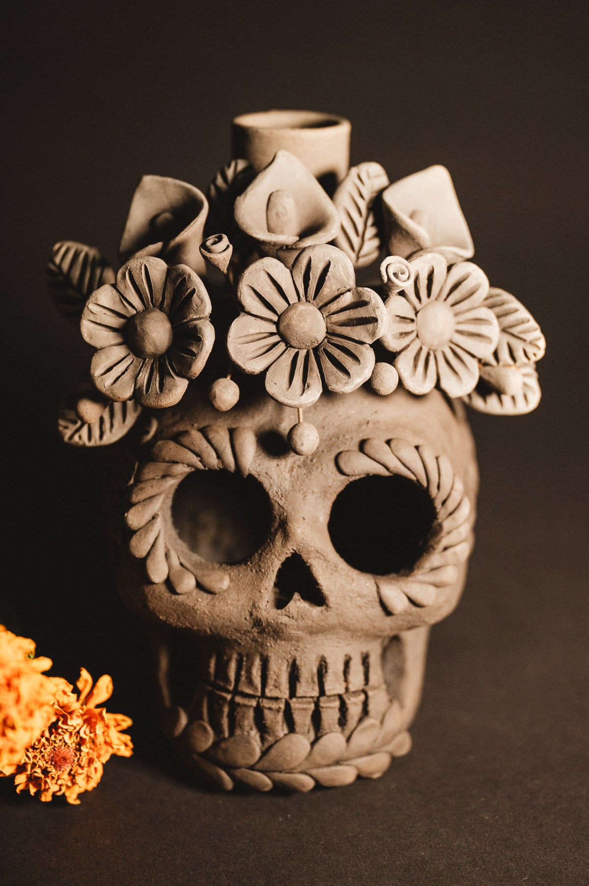 Ceramic skull vase with floral designs on a dark background