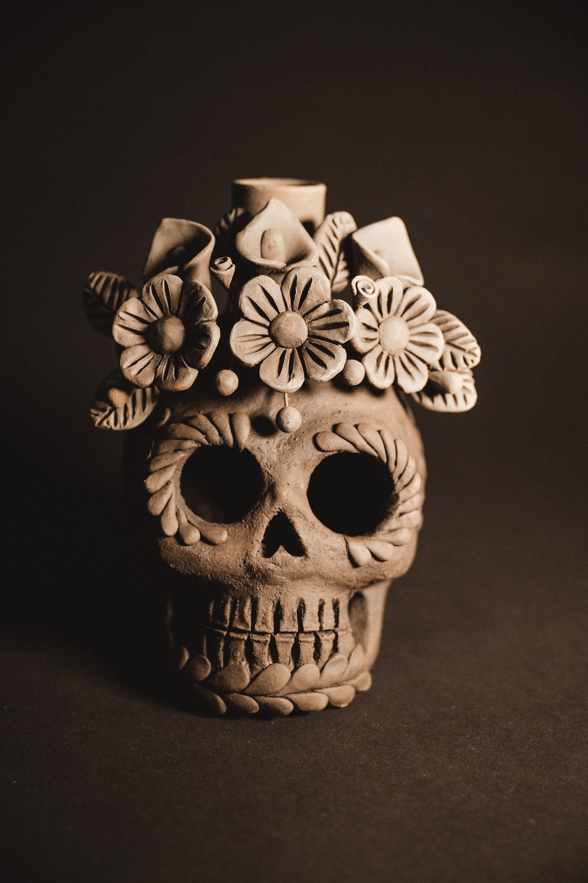 Clay skull with floral design on a dark background