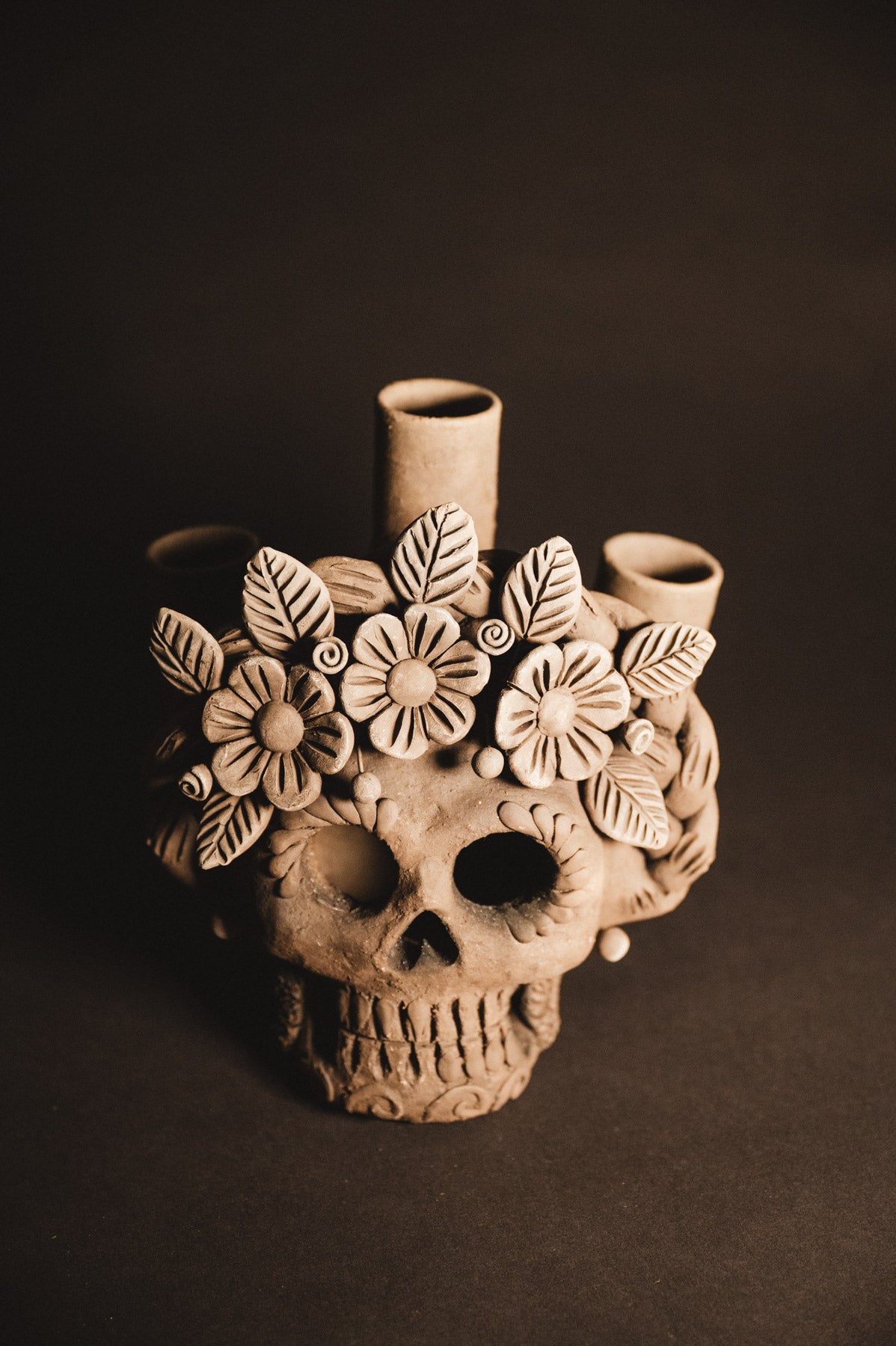 Ceramic skull vase with floral designs on a dark background