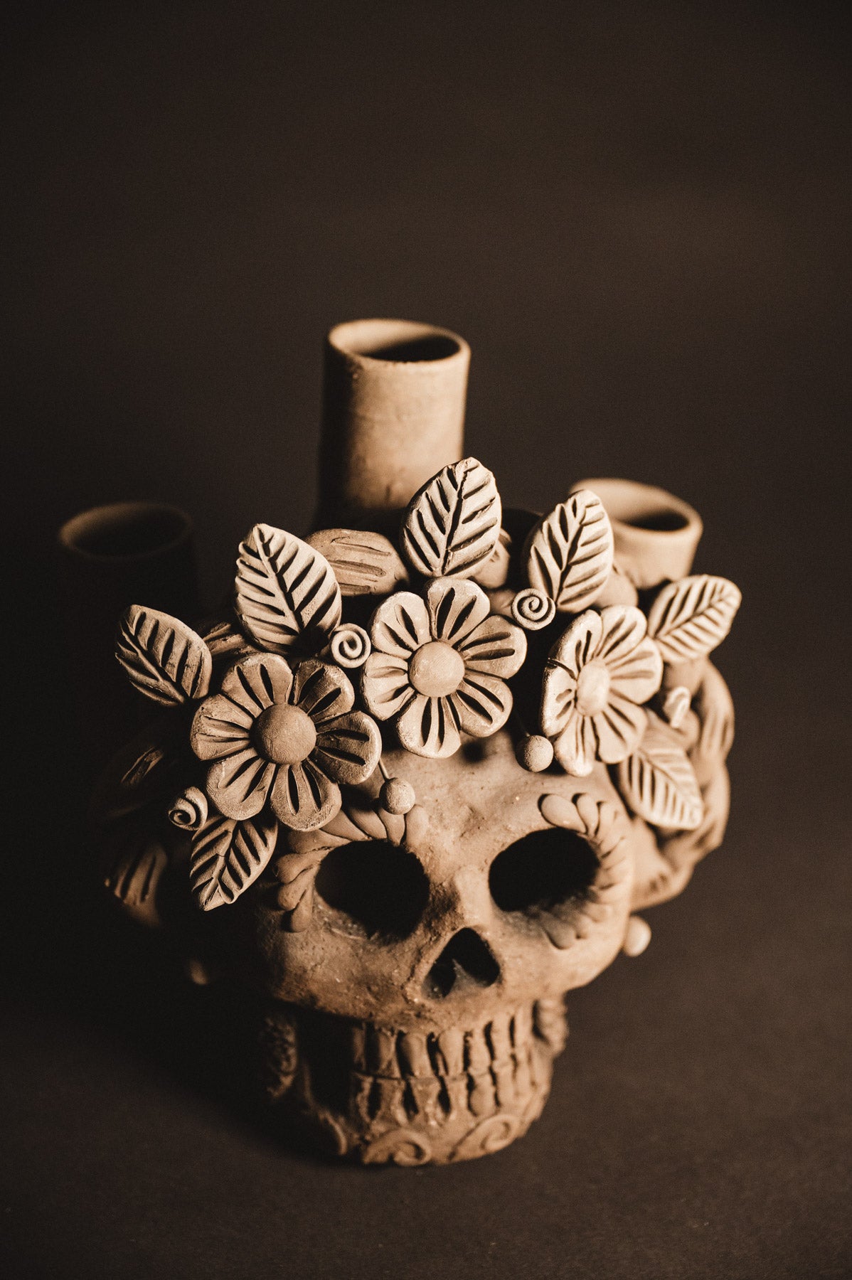 Ceramic skull vase with floral designs on a dark background