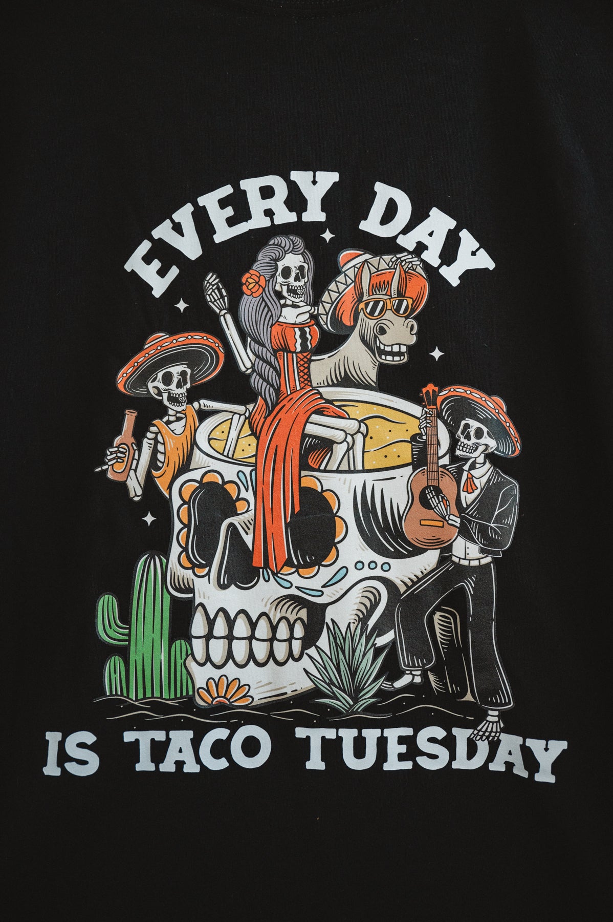 Black tshirt design close up hanging on a white brick wall