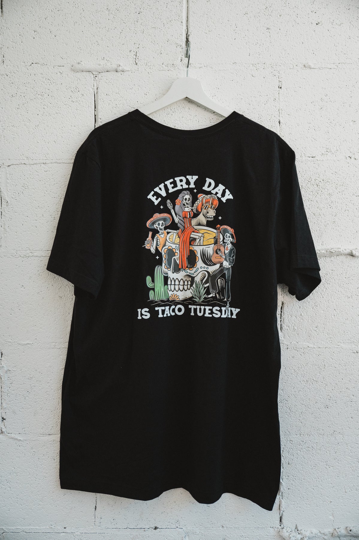 Black tshirt hanging on a white brick wall