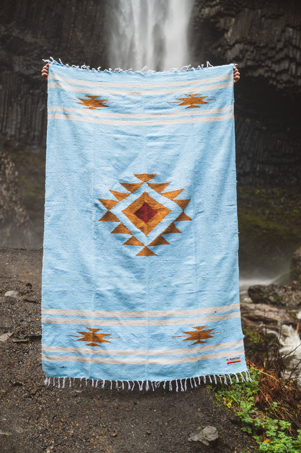 Blue patterned towel held up against a waterfall background