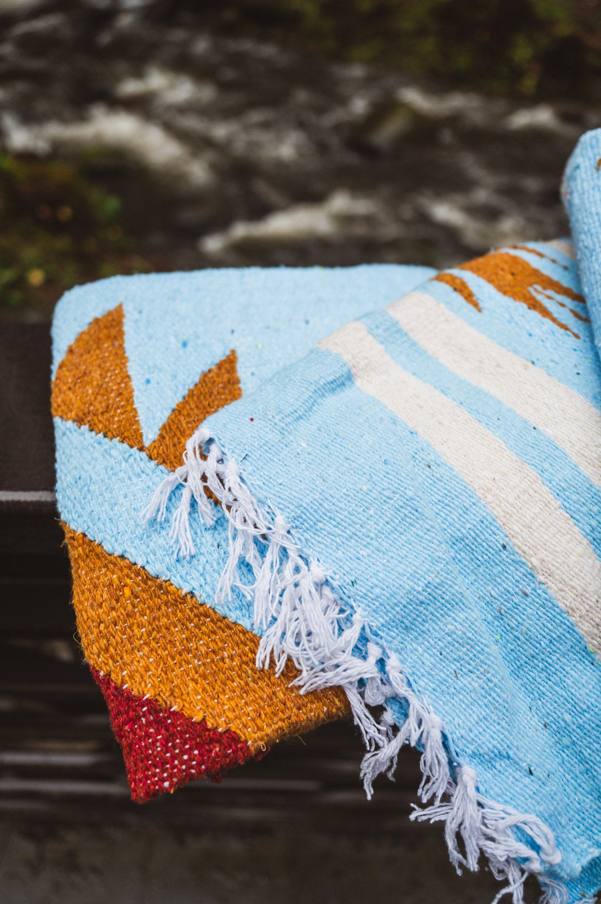 Colorful woven blanket with geometric pattern on a natural background