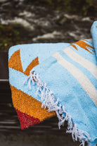 Colorful woven blanket with geometric pattern on a natural background